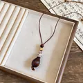 Close-up of ethnic style pendant necklace with dark brown nut and patterned bead - Seed Shape Style / Coffee