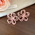 Primer plano de pendientes de flor rosa calada con un diseño dulce y elegante. - Estilo Floral Hueco (HE32264) / Rosa