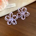 Detalle de cerca de los pendientes de botón de flores caladas moradas con un acabado mate - Estilo Floral Hueco (HE32264) / Púrpura