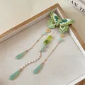 Gros plan sur une pince à cheveux papillon brodée verte avec des glands en perles - Pinces à cheveux bec de canard / Vert