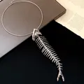 Close-up detail of silver metallic fishbone pendant on a minimalist neck ring - Silver