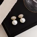 Close-up of elegant zircon oval pearl clip earrings displayed on a black tray backdrop - Clip-On Earrings / Gold-White