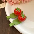 Détail de jolies pinces à cheveux tomates en résine sur une assiette avec fleurs roses - Tomate