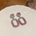 Elegant close-up of pink crystal drop earrings with pave diamonds on white ceramic plate - Pink