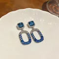 Detail of elegant dangling earrings with blue gemstones and white zircon pave setting. - Blue