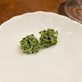 Macro view of olive green beaded flower stud earrings on a white ruffled plate - Flower Shape / Green