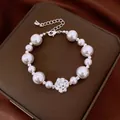 Detailed view of an elegant pearl bracelet with a sparkling zircon flower charm. - Silver-Pink