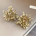 Vista dettagliata di orecchini a lobo a fiore dorati sfaccettati con trama fine - Oro