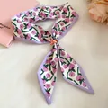 Close-up detail of a floral print silk scarf featuring a decorative wooden flower bead - Purple Print