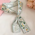Close-up of an elegant floral print silk scarf with a decorative wooden flower buckle - Green Flower