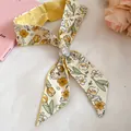 Close-up of floral print silk scarf with textured metal buckle detail. - Yellow Flower