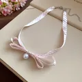 Primo piano di una collana a fiocco in nastro rosa a pois con pendente a perla bianca - Stile Nastro Rosa a Pois