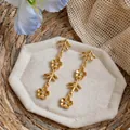 Dettaglio ravvicinato di orecchini vintage dorati con fiori di strass e motivi a rami eleganti. - Stile nappa floreale / Oro