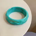 Close-up detail of turquoise acrylic faceted bangle with brown marble texture pattern - Cyan