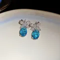 Détails des boucles d'oreilles nœud avec des cristaux ovales bleus éclatants. - Tige d'oreille en argent - Argent - Bleu