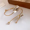Detail view of a gold-toned metal arm cuff with oval and round faceted crystals - Gold-Clear