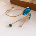 Detailed view of a gold arm cuff bracelet featuring faceted blue oval gemstones - Gold-Blue