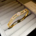 Detailed macro view of an 18K gold plated double layer bangle featuring a zircon flower - Style 3 / Gold