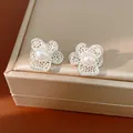 Nahaufnahme von filigranen Blumen-Ohrsteckern mit Zirkonia-Besatz und zentraler Perle - 925 Silber Stift Stil / Silber