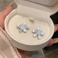 Close-up of elegant flower stud earrings with pearl-like petals in a white jewelry box - Flower Stud Earrings / Blue