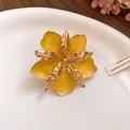 Gros plan sur une boucle d'oreille fleur jaune avec pétales en métal doré froissé - Bague / Jaune