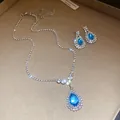 Macro view of blue teardrop pendant necklace and matching earrings set with rhinestones - Necklace Earrings Ensemble (Silver) / Blue