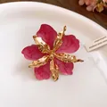 Gros plan détaillé montrant l'émail rose marbré et les pétales métalliques dorés de boucles d'oreilles - Bague / Rose rouge