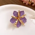 Gros plan détaillé d'une boucle d'oreille fleur en émail violet avec détails dorés - Bague / Violet