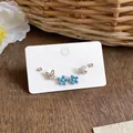 Detail showing rhinestone butterfly and blue enamel flower studs on a display card. - Butterfly Flower Enamel Style (HE33692) / Silver Earring Post - Silver - Blue