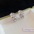 Vista macro dettagliata del motivo esagonale e dei brillantini sugli orecchini a forma di C - Stile Geometrico a C con Strass / Argento