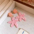 Detailed macro shot of elegant pink resin starfish earrings on a linen jewelry tray - Pink