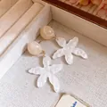 Detail of white marbled resin flower earrings with beige stud in a jewelry tray - White