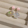 Macro view of clear resin earrings featuring playful colorful polka dots in a jewelry tray - Silver Earring Post Style / Pink