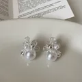 Detailed macro view of elegant floral pearl earrings accented with sparkling zirconia stones - Flower Shape / Silver-White