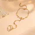 Vue détaillée du bracelet papillon doré avec gemmes roses et chaîne en acier titane. - Style Trois Papillons