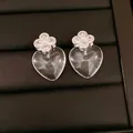 Close-up detail of silver needle earrings with zircon flower and clear resin hearts - Silver-Clear