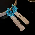 Close-up of elegant blue crystal flower earrings with long silver tassel chains - Silver-Blue