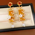 Détail rapproché de boucles d'oreilles carrées vintage avec fleurs, perles blanches et strass - Style Perle Botanique Vintage / Or-Blanc-Ambre