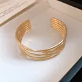 Nahaufnahme eines eleganten, goldfarbenen, mehrlagig gestreiften, offenen Armreifs für Damen - Mehrschichtig Fein Gestreift Verflochten Stil (Modell 7)