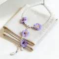 Dettaglio di una collana a Y con fiori in tessuto viola e perle bianche eleganti - Viola-Bianco