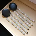 Detailed view of vintage-style black wooden earrings with elegant long white pearl tassels - Black With White Stone