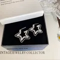 Dettaglio degli orecchini a stella a doppio strato in una scatola regalo elegante - Stile Stella a Doppio Strato / Argento