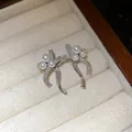 Close-up view of silver bow stud earrings featuring delicate pearls in a jewelry box. - Silver