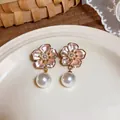 Close-up detail of elegant pink cherry blossom earrings featuring dangling round pearls - Gold-Pink