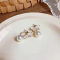 Detailed close-up view of butterfly pearl earrings with enamel petals and crystals - Gold-White