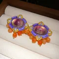Macro detail of luxury vintage palace style earrings with purple resin and orange beads. - Gold, Purple and Orange