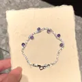 Detail of elegant zircon tennis bracelet with purple accents on textured paper background - Purple