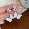 Detailed close-up of sparkling zirconia butterfly and flower drop earrings for women - Pink