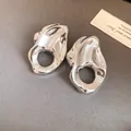 Primer plano de pendientes metálicos irregulares con textura arrugada y centro hueco - Aguja de plata / Plateado