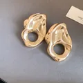 Detalle de pendientes dorados irregulares con un diseño plisado y calado hueco - Aguja de plata / Dorado